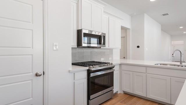 kitchen featuring sink, light hardwood / wood-style floors, white cabinets, and appliances with stainless steel finishes