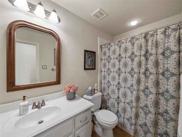 bathroom featuring toilet, walk in shower, and vanity