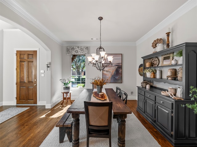 dining area featuring dark wood-type flooring, crown molding, and a notable chandelier