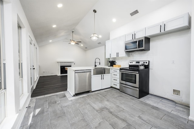 kitchen with sink, white cabinets, stainless steel appliances, and lofted ceiling