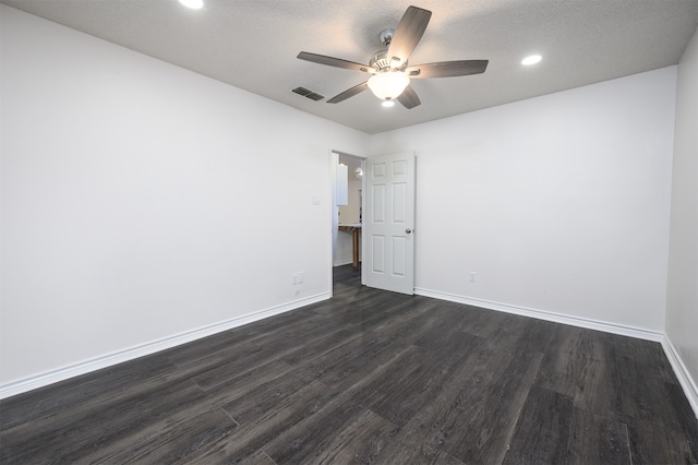 spare room featuring baseboards, visible vents, a ceiling fan, dark wood-style flooring, and a textured ceiling