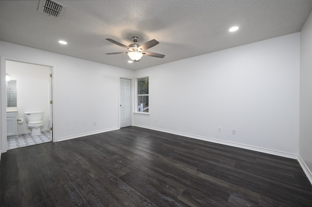 unfurnished bedroom featuring a textured ceiling, dark wood-style flooring, visible vents, and baseboards