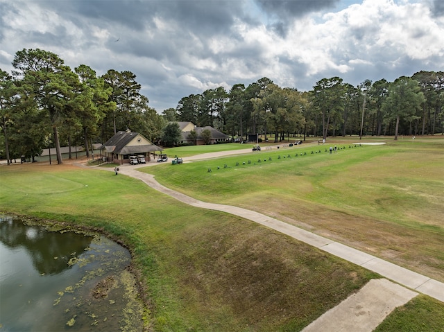 view of home's community with a water view, view of golf course, and a yard