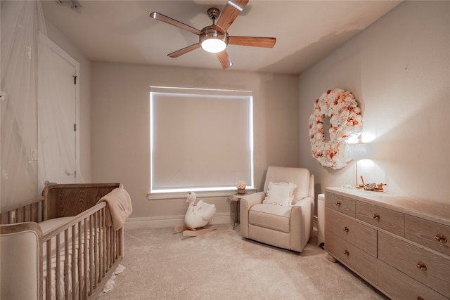 bedroom with ceiling fan, light carpet, and a crib