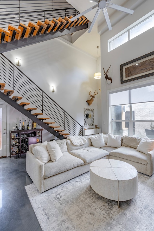 living room with concrete flooring, a towering ceiling, and ceiling fan