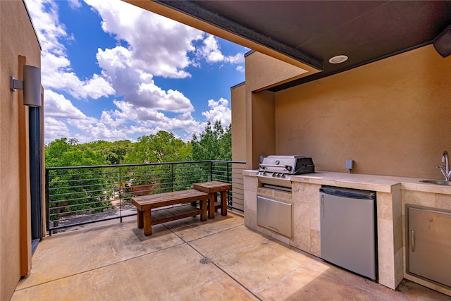 view of patio featuring a balcony, an outdoor kitchen, sink, and area for grilling