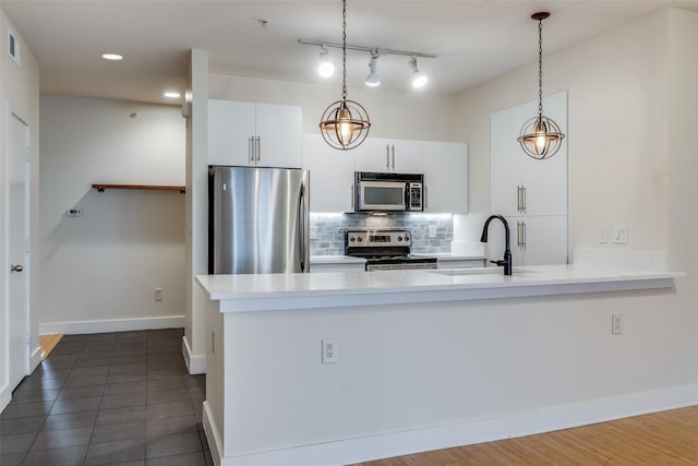 kitchen with sink, stainless steel appliances, backsplash, pendant lighting, and white cabinets