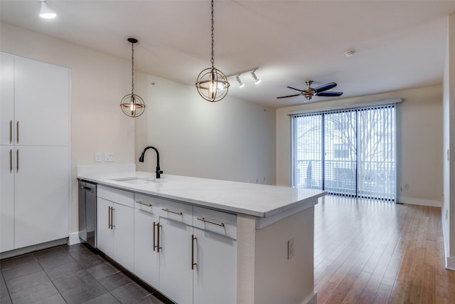 kitchen with pendant lighting, kitchen peninsula, sink, light stone countertops, and white cabinetry