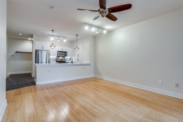 unfurnished living room with rail lighting, ceiling fan, sink, and light hardwood / wood-style flooring