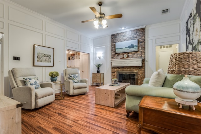 living room featuring ornamental molding, a fireplace, wood-type flooring, and ceiling fan