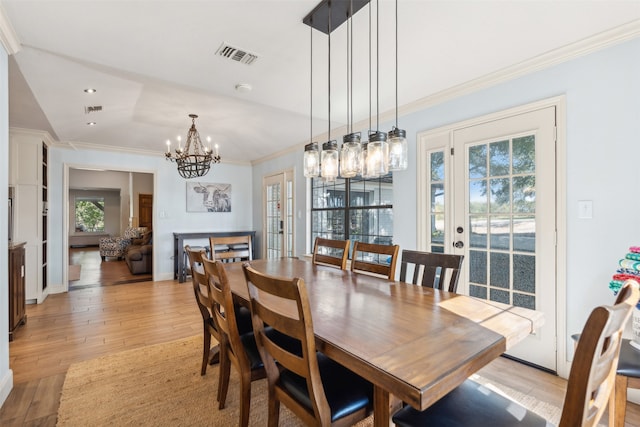 dining area with a chandelier, a healthy amount of sunlight, light hardwood / wood-style flooring, and crown molding