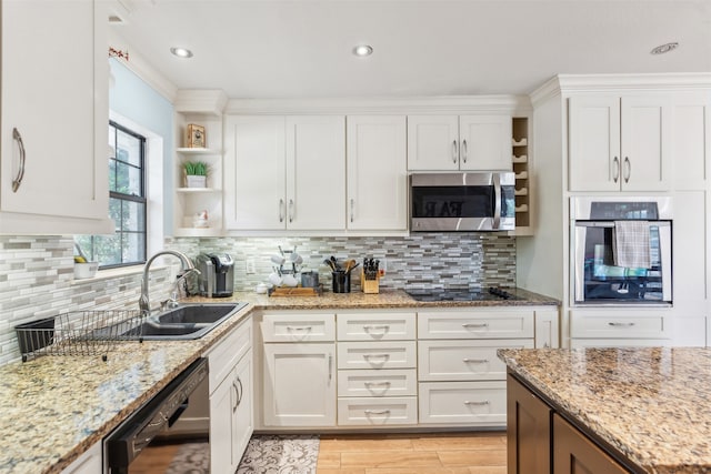 kitchen with light stone counters, white cabinets, black appliances, sink, and tasteful backsplash