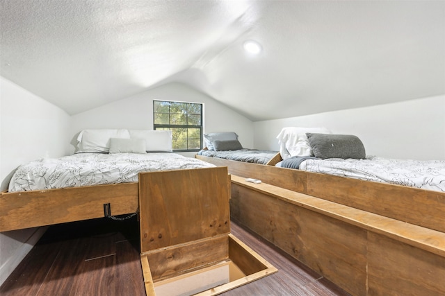 bedroom featuring dark wood-type flooring, lofted ceiling, and a textured ceiling