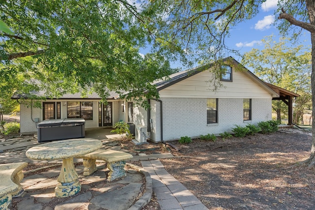 rear view of property featuring a hot tub and a patio area