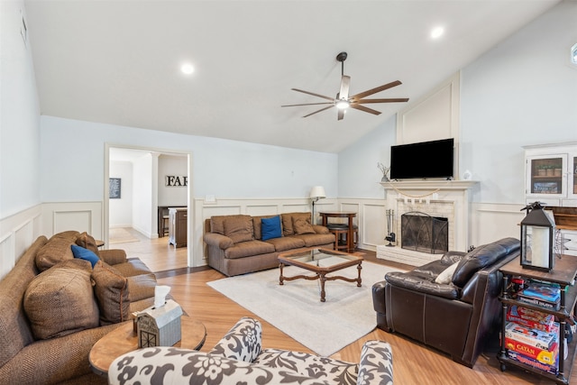 living room featuring high vaulted ceiling, a fireplace, ceiling fan, and light hardwood / wood-style flooring