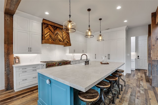 kitchen featuring white cabinets, high end stainless steel range oven, a spacious island, a kitchen bar, and light wood-type flooring