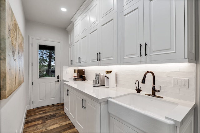 bar with dark wood-type flooring, decorative backsplash, and white cabinets