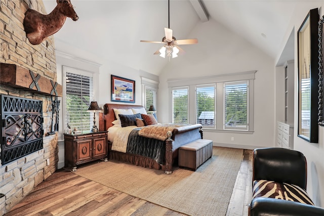 bedroom featuring multiple windows, beam ceiling, light wood-type flooring, and ceiling fan