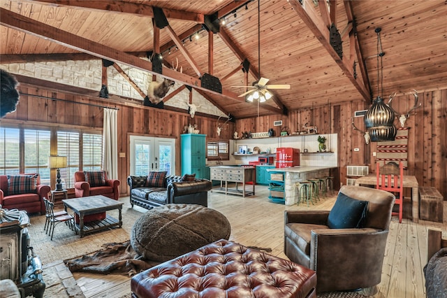 living room with beam ceiling, wooden walls, wooden ceiling, light wood-type flooring, and high vaulted ceiling