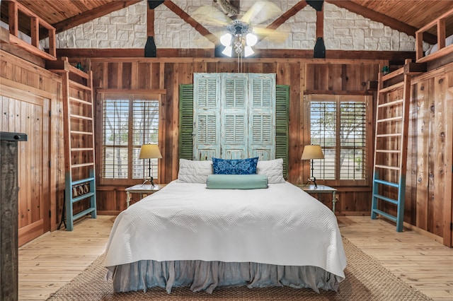 bedroom with light wood-type flooring, wood ceiling, and wooden walls