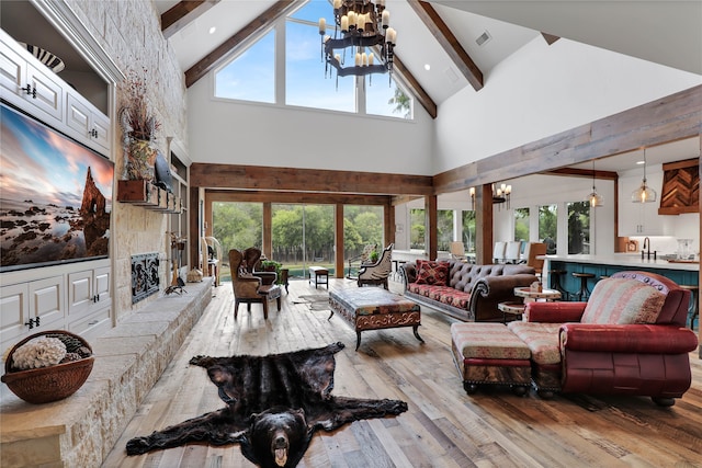 living room with light hardwood / wood-style floors, a healthy amount of sunlight, a chandelier, and high vaulted ceiling