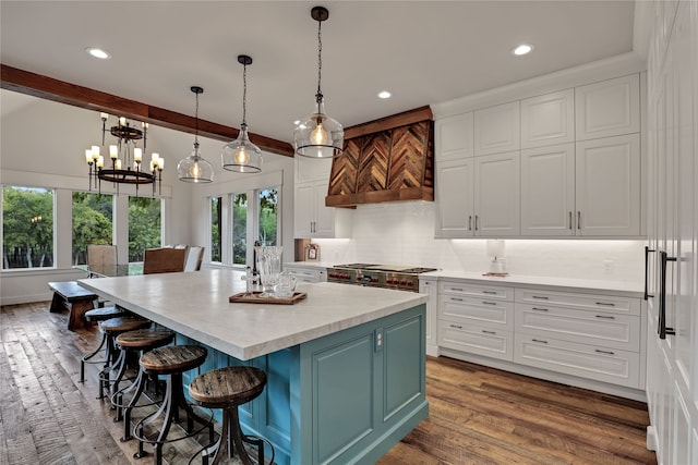 kitchen with a center island, hardwood / wood-style floors, white cabinetry, pendant lighting, and stainless steel stove