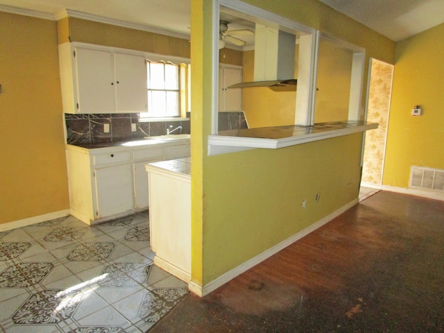 kitchen with decorative backsplash, white cabinetry, and crown molding