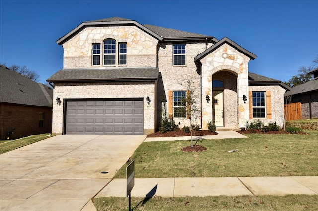 french provincial home featuring a front yard and a garage