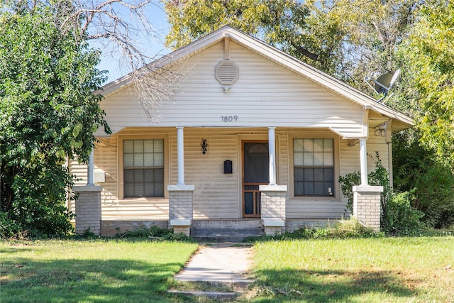 bungalow-style house featuring covered porch and a front lawn
