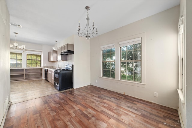 kitchen with a sink, wood finished floors, black appliances, under cabinet range hood, and a chandelier