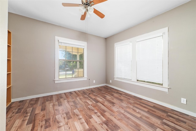 empty room featuring wood finished floors, baseboards, and ceiling fan