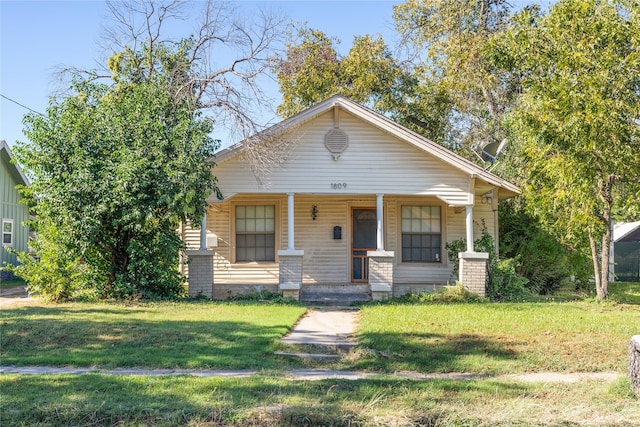 bungalow-style home with covered porch and a front yard