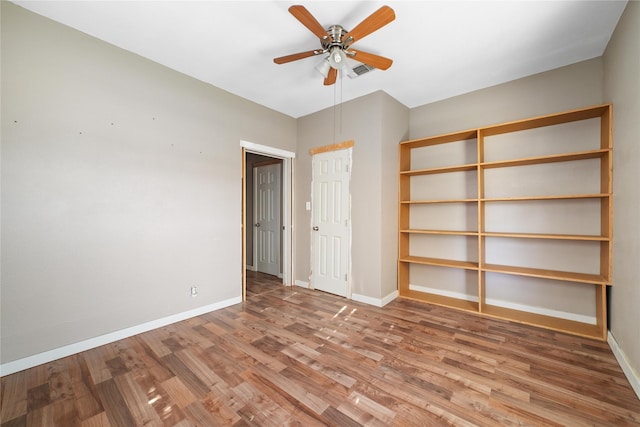 empty room with baseboards, wood finished floors, and a ceiling fan