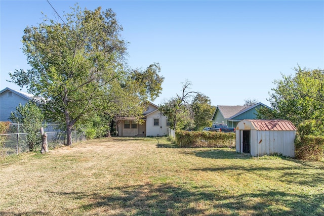view of yard featuring a storage shed, fence, and an outbuilding