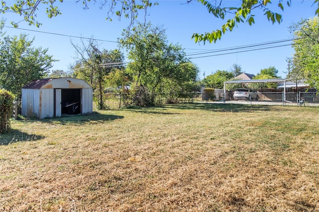 view of yard featuring a carport, an outdoor structure, a fenced backyard, and a shed