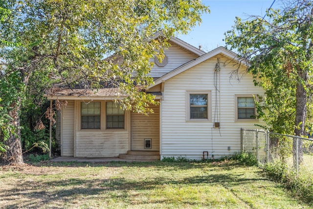 back of house featuring a lawn and fence