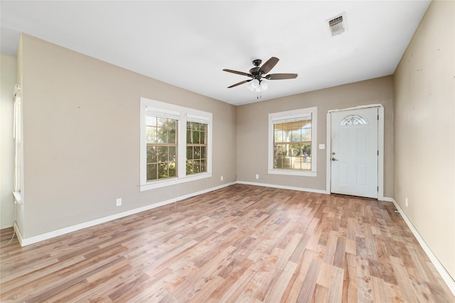 interior space featuring baseboards, visible vents, light wood-style flooring, and a ceiling fan