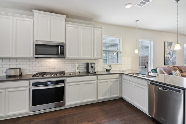 kitchen with appliances with stainless steel finishes, sink, decorative light fixtures, white cabinets, and dark hardwood / wood-style floors