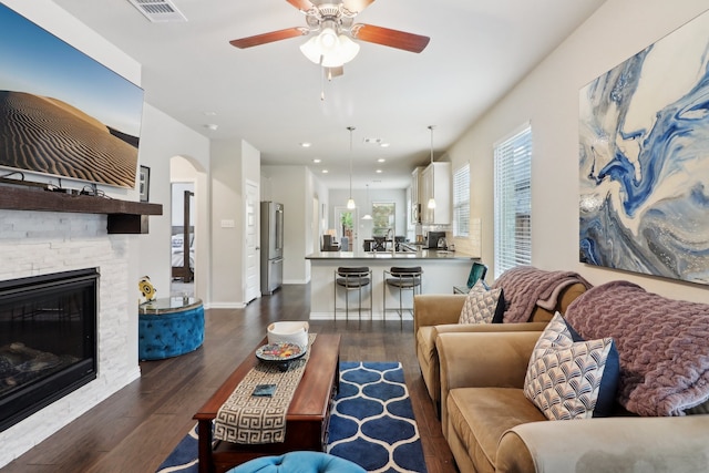 living room with dark wood-type flooring, ceiling fan, and a fireplace