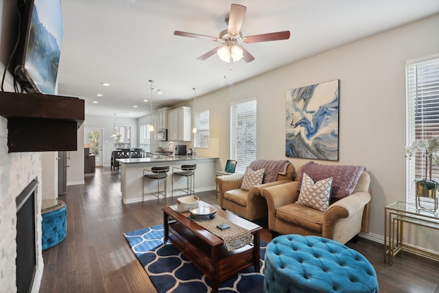 living room with ceiling fan, a healthy amount of sunlight, a fireplace, and dark hardwood / wood-style floors