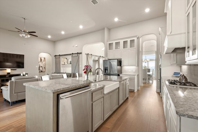 kitchen with white cabinetry, appliances with stainless steel finishes, a barn door, and a large island