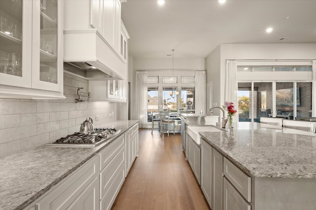 kitchen with stainless steel gas cooktop, dark hardwood / wood-style floors, sink, pendant lighting, and white cabinetry