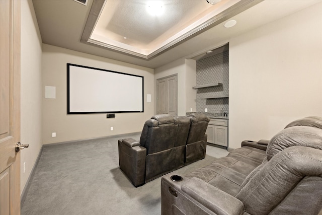 home theater room with light colored carpet and a raised ceiling