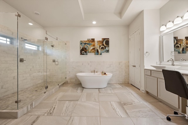 bathroom with vanity, a raised ceiling, tile walls, and plus walk in shower