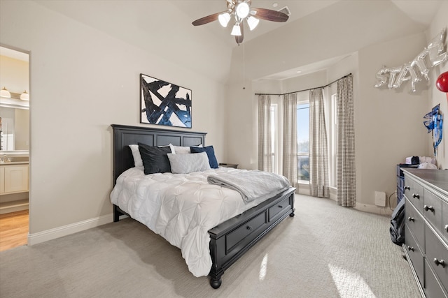 bedroom with ensuite bath, vaulted ceiling, light carpet, and ceiling fan