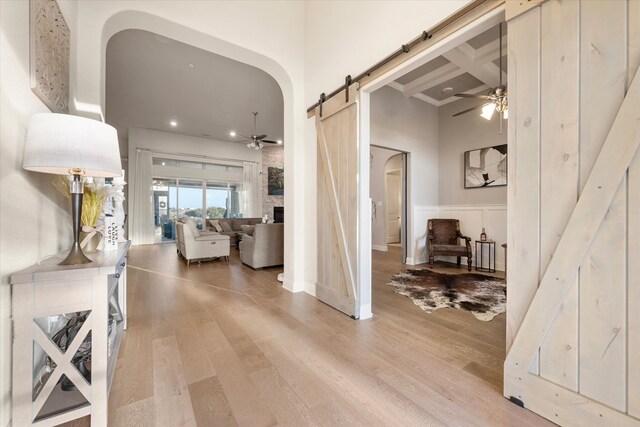 corridor featuring coffered ceiling, beamed ceiling, light wood-type flooring, and a barn door