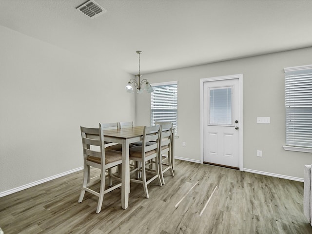 dining area with light hardwood / wood-style floors and a chandelier