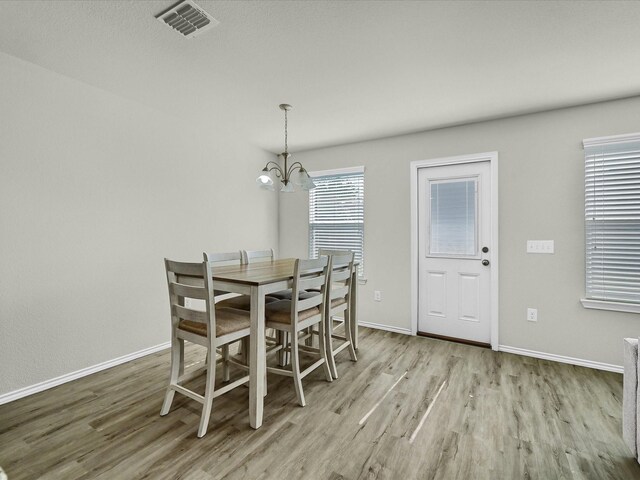 dining area featuring a notable chandelier, sink, and light wood-type flooring