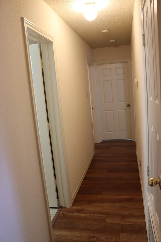 hall featuring a textured ceiling and dark hardwood / wood-style floors