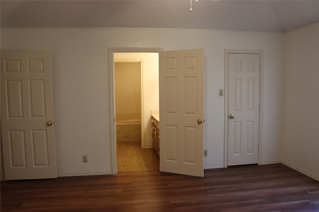 unfurnished bedroom featuring lofted ceiling, connected bathroom, and dark hardwood / wood-style flooring